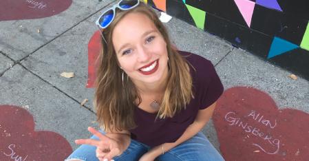 au pair sitting on the pavement, smiling into the camera