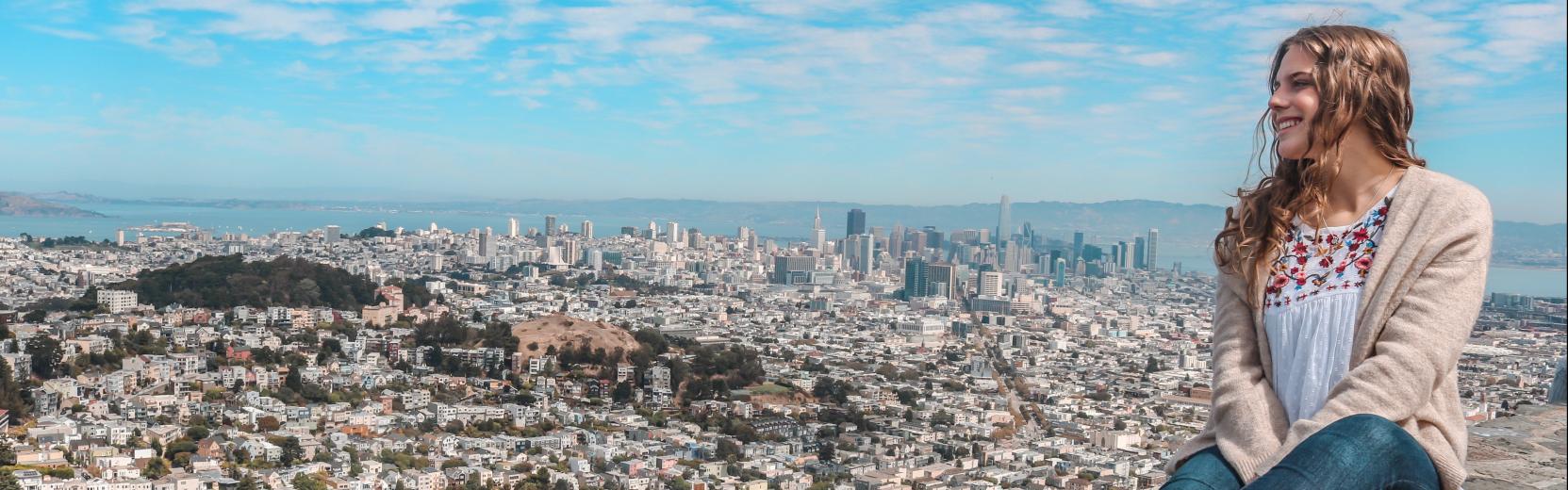 au pair sitting on a wall overlooking a city